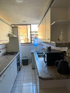 uma cozinha com armários brancos e uma bancada em Departamento Los Delfines em Iquique