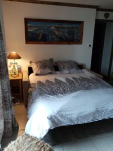 1 dormitorio con 1 cama y 1 mesa con lámpara en les 7 laux immobilier chalet E, en Prapoutel