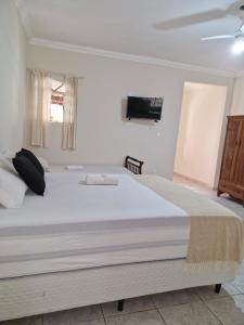 um quarto com uma cama grande e uma televisão na parede em Encantu's Flats em Itatiaia