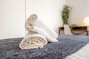 uma pilha de toalhas brancas sentadas numa cama em Santos Mattos Guesthouse & Apartments by Lisbon with Sintra na Amadora