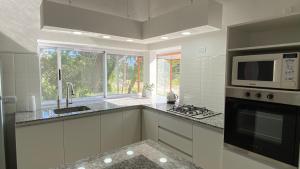 Casa Ama-gi في ميرلو: مطبخ أبيض مع ميكروويف وموقد