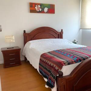 a bedroom with a bed and a table with a lamp at Habitaciones cerca del aeropuerto in Bogotá