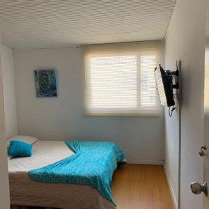 a bedroom with a bed with a blue blanket and a window at Habitaciones cerca del aeropuerto in Bogotá
