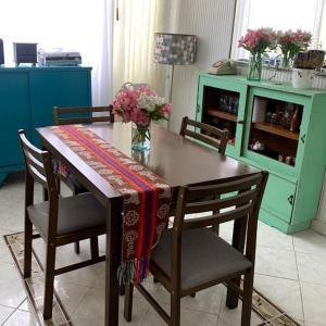 a dining room table with chairs and a vase of flowers at Habitaciones cerca del aeropuerto in Bogotá