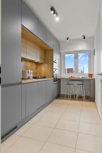 a kitchen with gray cabinets and a white tile floor at Mido Park Apartment with Private Parking in Bucharest