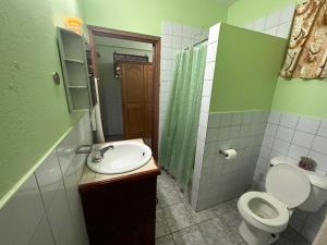 baño verde con aseo y lavamanos en Homely environment ideal for a home away from home en Gros Islet