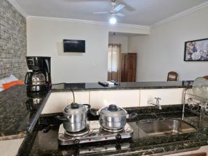 uma cozinha com duas panelas num fogão com um lavatório em Encantu's Flats em Itatiaia
