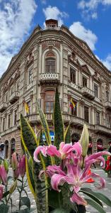 Floré Hotel Boutique Cuenca في كوينكا: مبنى كبير أمامه زهور وردية