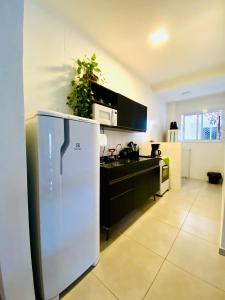uma cozinha com um frigorífico branco num quarto em Ap no centro piscina e churras em Ubatuba