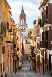 an alley between two buildings with a clock tower at Bonito estudio en el centro. Ideal parejas. in Palamós