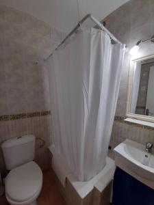 a bathroom with a toilet and a sink and a shower curtain at Bonito estudio en el centro. Ideal parejas. in Palamós