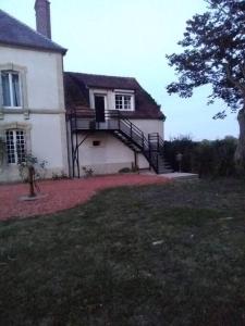 a large white house with a staircase in the yard at la mansarde in La Cochère
