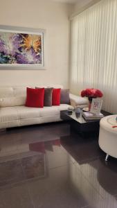 Casa Provenza Bucaramanga في بوكارامانغا: غرفة معيشة مع أريكة بيضاء ووسائد حمراء