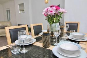 a dining room table with a vase of flowers and glasses at 3Bed Gem Near Coventry Building Society Arena in Coventry