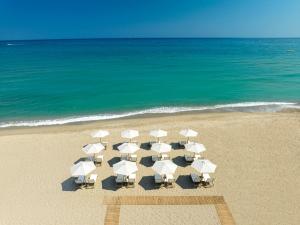 eine Gruppe von Stühlen und Sonnenschirmen am Strand in der Unterkunft Calla Luxury Seafront Suites in Rethymno