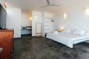 a bedroom with a white bed and a television at Marmot Seashore Moonset Suite in Máncora