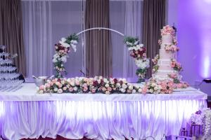 a table with a wedding cake and flowers on it at Mayberry Highway - Apartmani Medijapark in Sveti Nikole