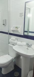 ein weißes Bad mit einem WC und einem Waschbecken in der Unterkunft Hostal Restaurante La Giralda in Rota