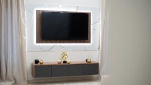 a television on a white wall with a table with a tv at Barbarossa House in Kalabaka