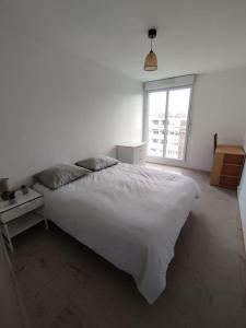 a bedroom with a large white bed and a window at Appartement Courbaril à Nantes (6) in Nantes