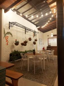 un restaurante con mesas, sillas y macetas en la pared en Volarte Hostal en Jardín