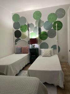 um quarto com duas camas e uma parede com círculos verdes em ACM Flat em Natal