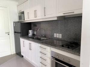 a kitchen with white cabinets and a sink at Depto PB con Jardín - Green Park in Punta del Este