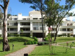 a large white building with trees in front of it at Depto PB con Jardín - Green Park in Punta del Este