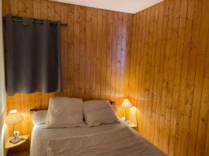 - une chambre avec des murs en bois et un lit avec deux lampes dans l'établissement Appartement Valloire, 2 pièces, 4 personnes - FR-1-263-422, à Valloire