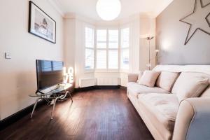 a living room with a couch and a tv at Chic 3-Bedroom Family Retreat in Stratford, Fast internet and near shops in London