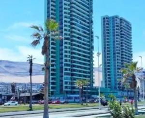 a tall building with palm trees in a city at Agua Marina Iqq in Iquique