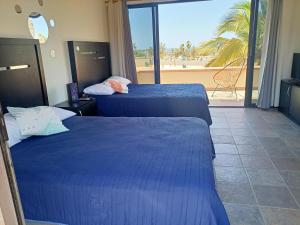 two beds in a hotel room with a view of the beach at Hostal San Jose in San José del Cabo
