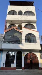 Hospedaje turístico Peruvian Wasi في ليما: مبنى أبيض طويل مع نوافذ وأبواب كبيرة