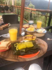 una mesa con platos de comida y vasos de zumo de naranja en Villa Colombia en Vianí