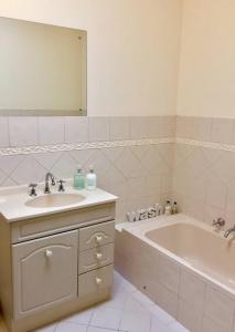 a bathroom with a sink and a tub and a mirror at Goodwood 3BR Close to City! in Wayville