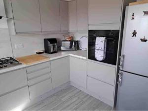 a kitchen with white cabinets and a refrigerator at Binks Bungalow in Hunstanton