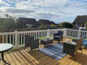 a deck with chairs and a table and a white fence at Binks Bungalow in New Hunstanton