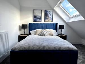 a bedroom with a blue bed and two windows at Brand new modern Cheltenham home 