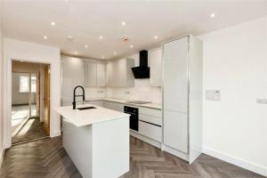 a white kitchen with white cabinets and a sink at Brand new modern Cheltenham home 