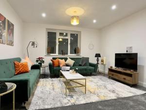 a living room with green couches and a flat screen tv at Brand new modern Cheltenham home 