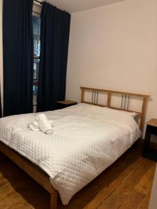 um quarto com uma cama com lençóis brancos e uma janela em Room137 Stay in Stoke Newington em Londres