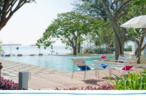 uma piscina com cadeiras, uma mesa e um guarda-sol em The Chelona em Khao Tao