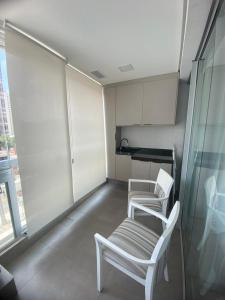 2 białe krzesła w pokoju z kuchnią w obiekcie Studio 2 Patteo Helbor - MAIA w mieście Guarulhos