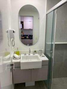 W białej łazience znajduje się umywalka i lustro. w obiekcie Studio 2 Patteo Helbor - MAIA w mieście Guarulhos