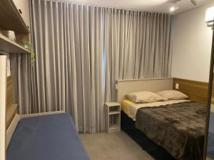 um quarto com uma cama e uma janela com cortinas em Studio 2 Patteo Helbor - MAIA em Guarulhos