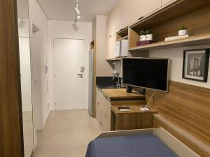 uma sala de estar com uma televisão de ecrã plano numa secretária em Studio 2 Patteo Helbor - MAIA em Guarulhos