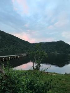 un puente sobre un lago con montañas en el fondo en Camping Refúgio Shakti II, en Florianópolis