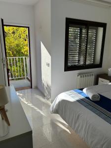 a white bedroom with a bed and a balcony at Appartement Duplex Rosas avec terrasse magnifique jacuzzi vue mer in Roses +38 photos