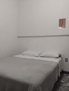 um quarto branco com uma cama com uma parede branca em Fine Guest em Belo Horizonte