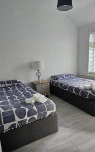 a bedroom with two beds and a table with a lamp at The Crescent, 3 bed house with 2-3 parking spaces, great for contractors and family in Kent